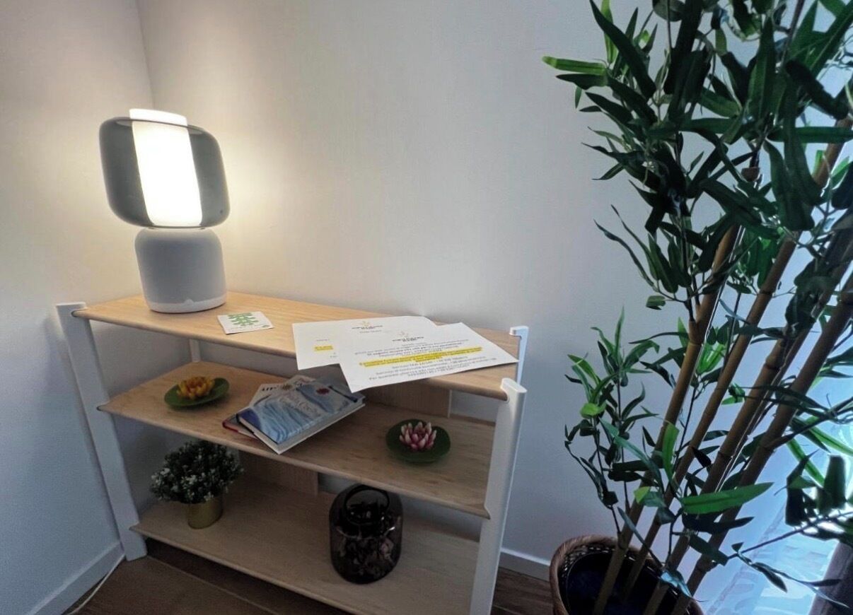 A corner desk with a lamp, papers, a small plant, and a bamboo plant.