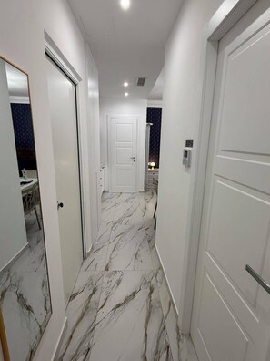 A hallway with white doors, marble flooring, and a ceiling light. - LUMìA Vatican Suite – Modernity and Comfort in the Heart of Rome (Roma)