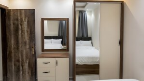 Ein Hotelzimmer mit zwei Betten, einem Holzschrank, einem Spiegel und einer Badezimmertür.