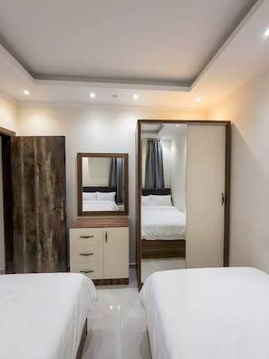 Une chambre d’hôtel avec deux lits, une armoire en bois, un miroir et une porte de salle de bain.