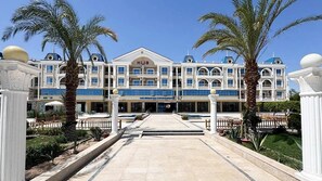 Un hôtel doté d’une entrée principale, de nombreux balcons et de palmiers.