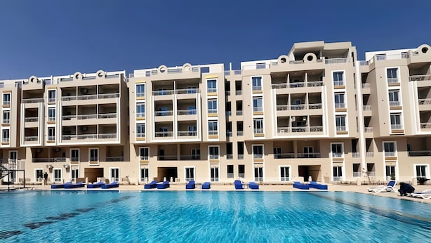 Ein mehrstöckiges Hotel mit Schwimmbad, Balkonen und blauem Himmel.