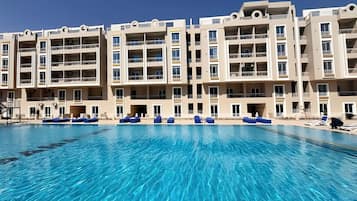 Ein mehrstöckiges Hotel mit Schwimmbad, Balkonen und blauem Himmel.
