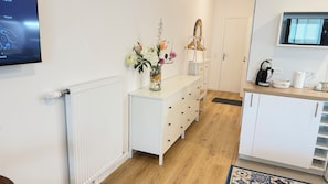 A modern kitchen with white cabinetry, a wooden countertop, and a decorative vase with flowers.