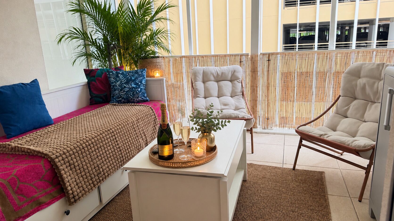 Un salon moderne avec un canapé, un fauteuil et une table basse sur laquelle se trouvent une bouteille et des verres.