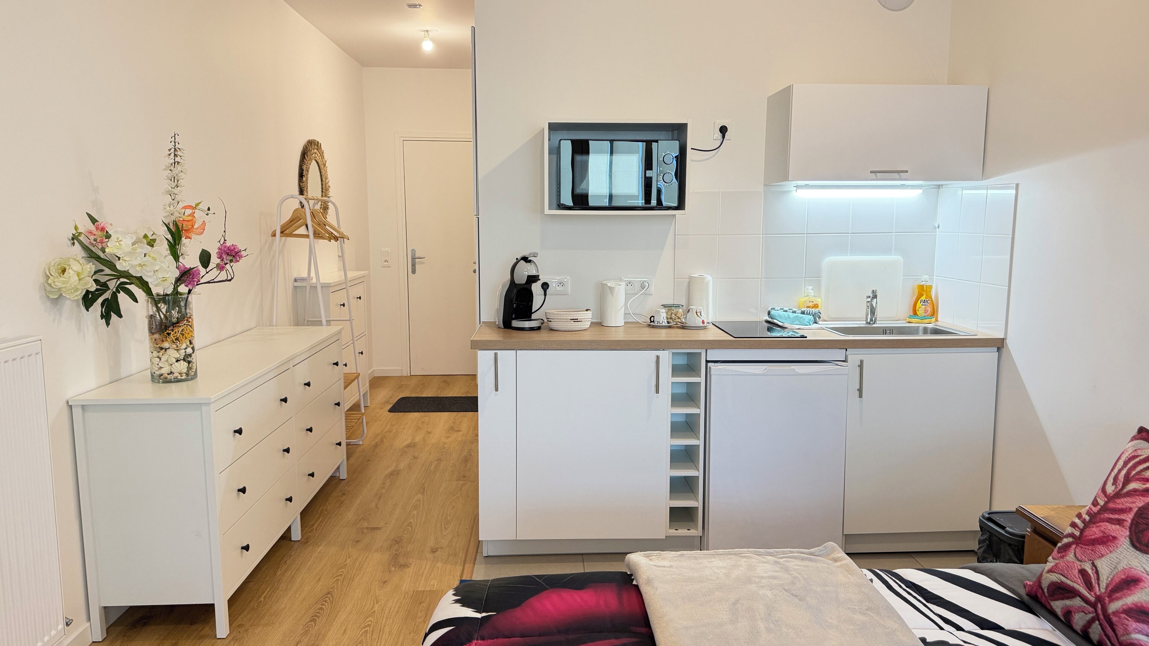 Een kleine keuken met een magnetron, koffiezetapparaat en een spoelbak.