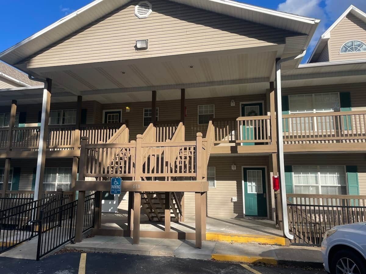 A multi-story hotel with a covered entrance, a wheelchair-accessible ramp, and a parking sign.