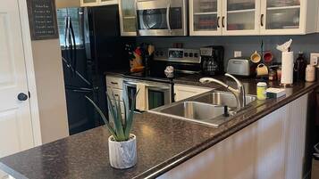 A modern kitchen with a central island, stainless steel appliances, and a backsplash.
