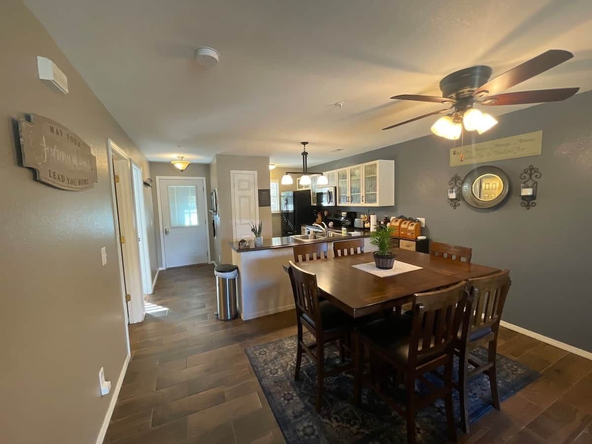 A spacious kitchen with a dining area, wooden flooring, and a ceiling fan.