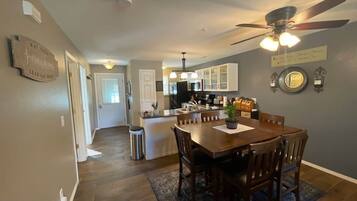 A spacious kitchen with a dining area, wooden flooring, and a ceiling fan.