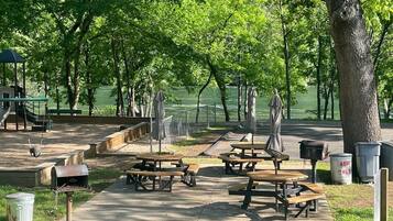 Ein Park mit Picknicktischen, Bänken und einem Spielplatz.
