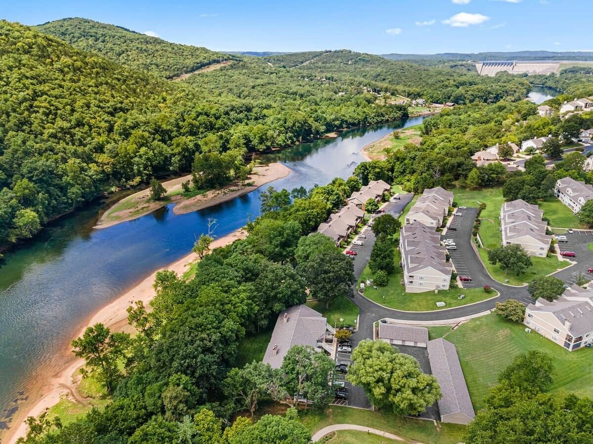 A residential area with houses, a river, and a dam in the background.
