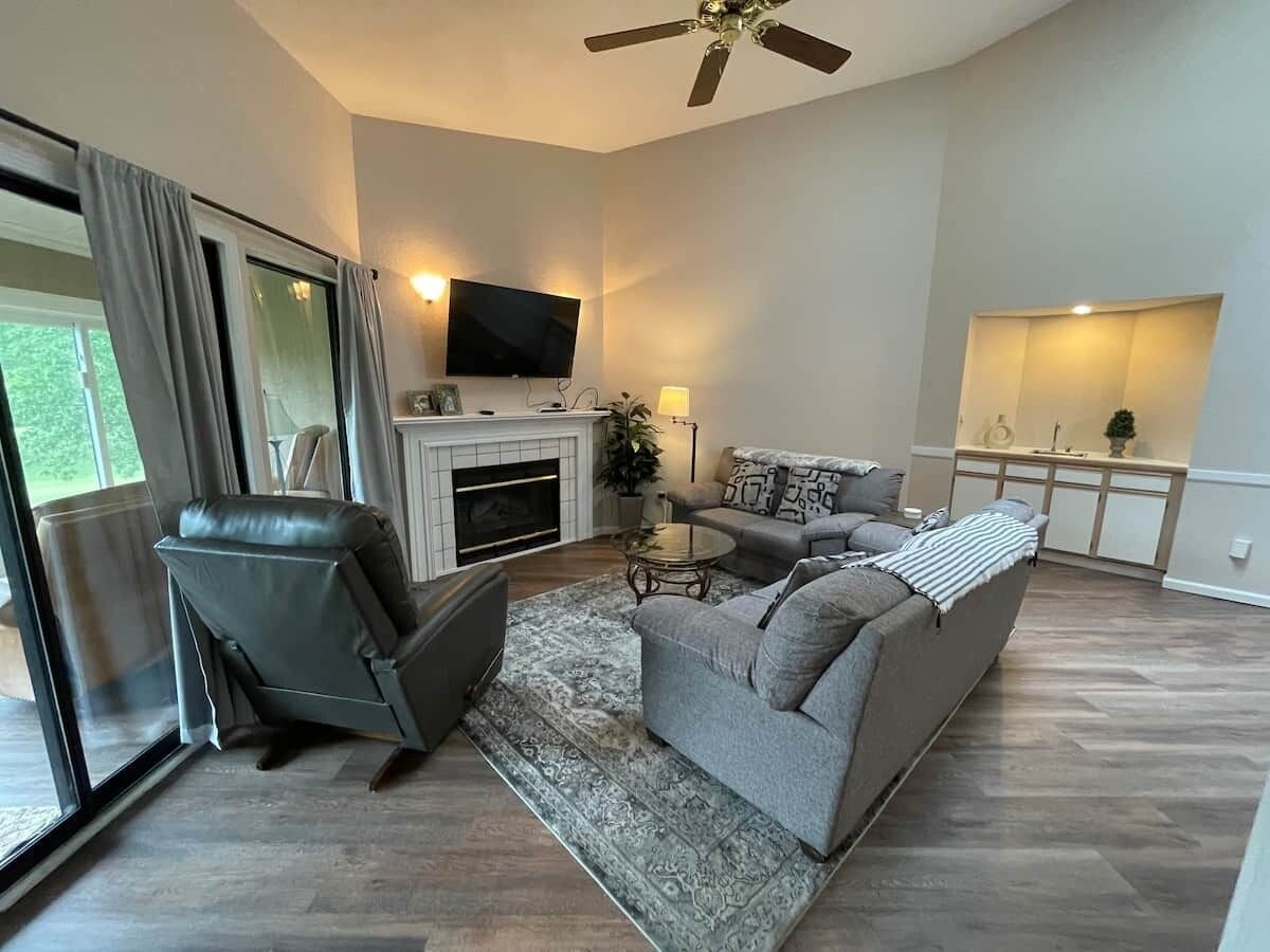A modern living room with a fireplace, a sofa, a chair, and a television.