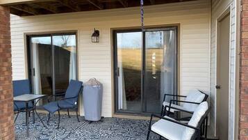 A covered patio with a table and chairs, a trash can, and a hanging light fixture.