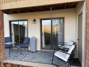 A covered patio with a table and chairs, a trash can, and a hanging light fixture. - Pointe Royale Ground Level Walk-In With Golf View (Branson)