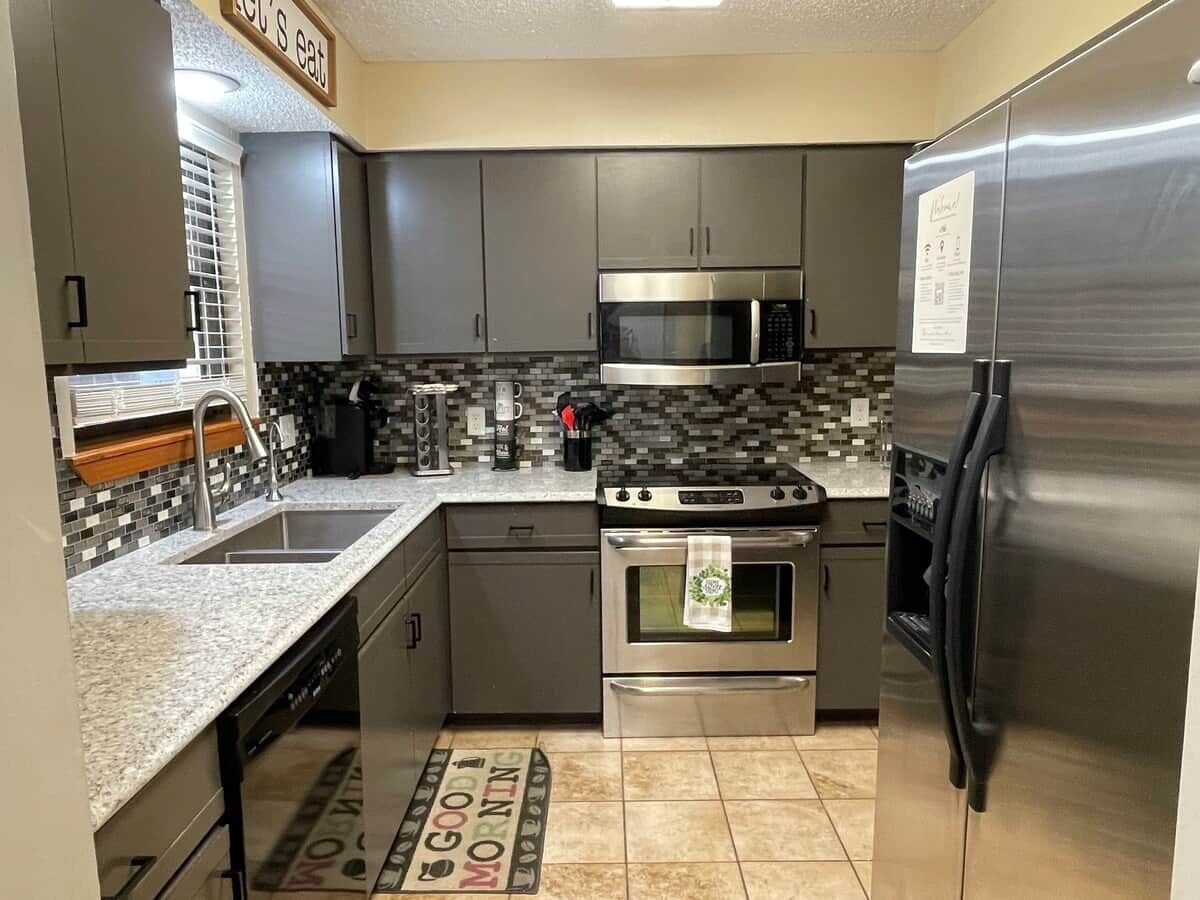 A modern kitchen with stainless steel appliances, a tiled backsplash, and a kitchen island.