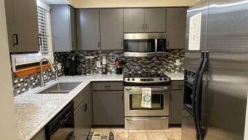A modern kitchen with stainless steel appliances, a tiled backsplash, and a kitchen island.