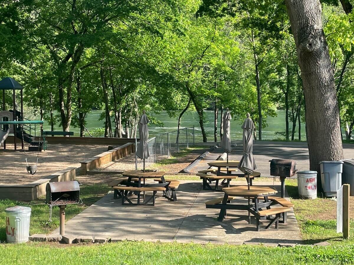 A park with picnic tables, benches, and a playground.
