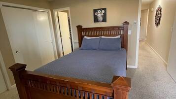 A bedroom with a wooden bed, a ceiling fan, and a carpeted floor.