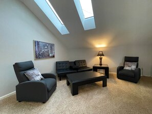 A living room with a sofa set, a coffee table, a lamp, and a painting on the wall. - Golf Front 4 Bedroom (Branson)