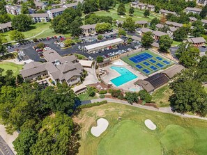 Vue aérienne d’un quartier résidentiel avec une piscine, des courts de tennis et un parcours de golf.