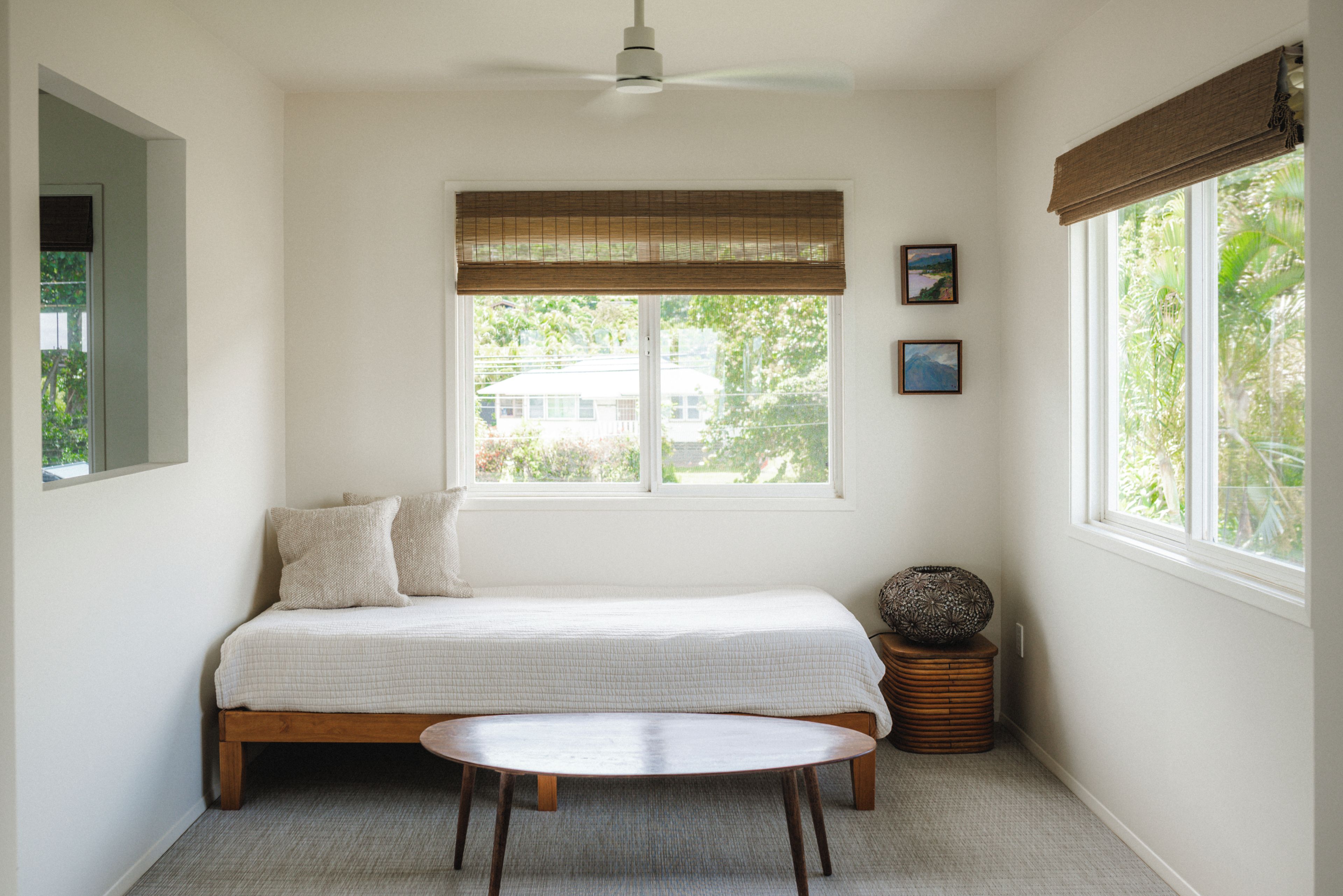 A bedroom with a bed, a round table, a window with a view, and a ceiling fan.