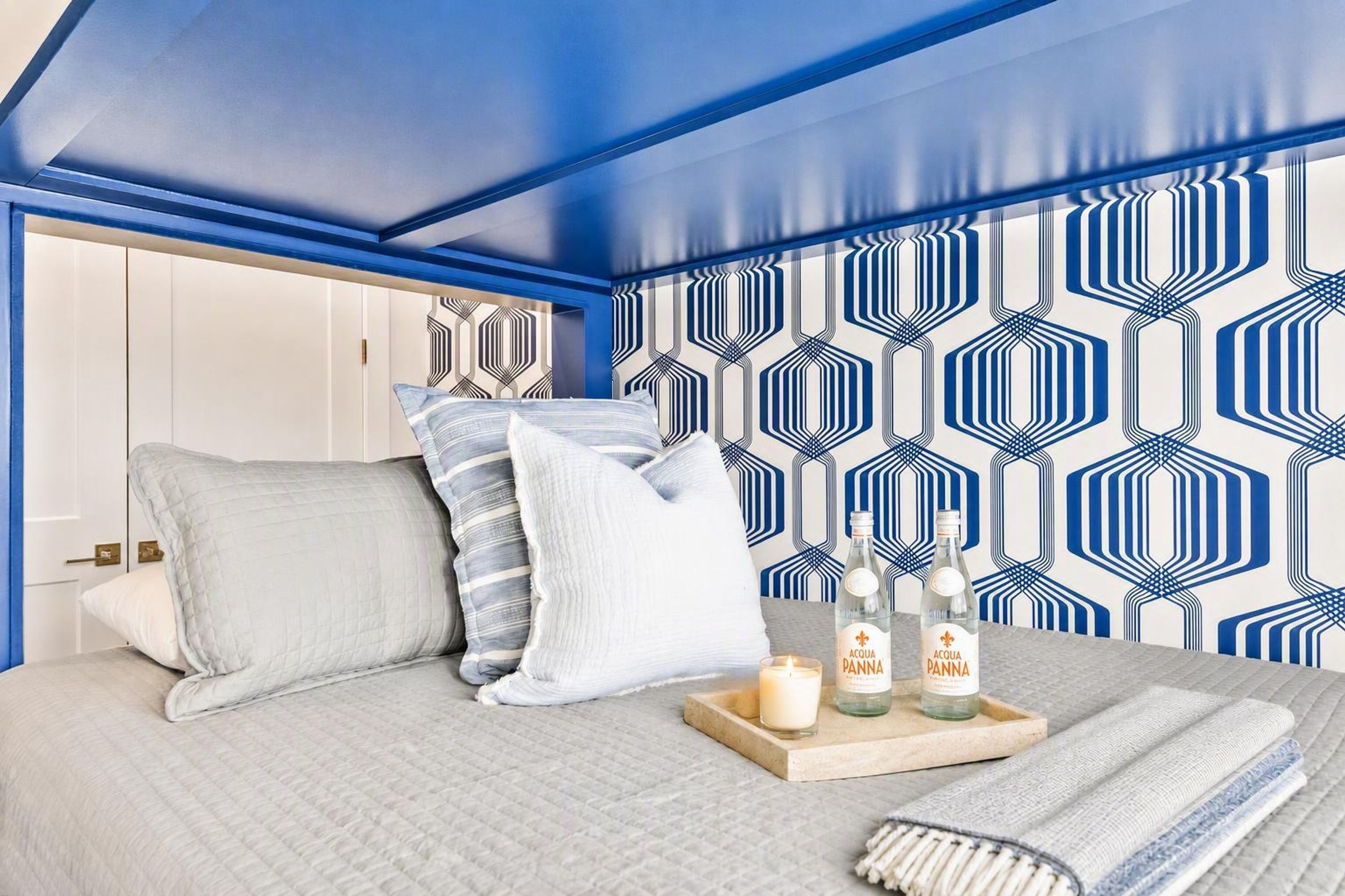 A bedroom with a bed, pillows, a tray with candles, and a bottle of water.