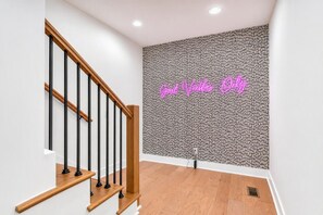 A staircase with wooden handrails and a patterned wall with a neon sign. - 3 Homes Side by Side Rooftop Deck Sleeps 36 (Nashville)