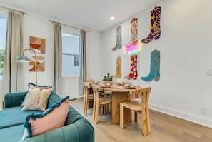 A dining area with a wooden table, chairs, and a neon sign on the wall. - 3 Homes Side by Side Rooftop Deck Sleeps 36 (Nashville)
