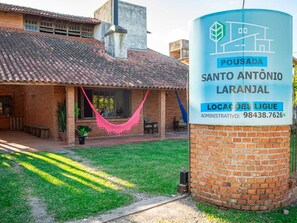 A residential property with a brick exterior, a tiled roof, and a grassy yard. - pousada santo antonio (Pelotas)