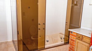 A bathroom with a glass-enclosed shower, a white toilet, and a bathtub. - pousada santo antonio (Pelotas)
