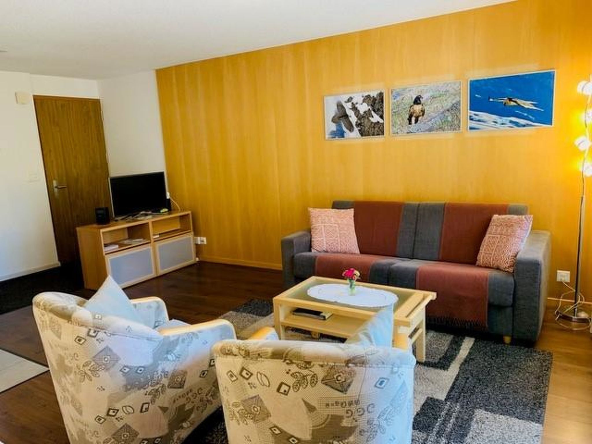 Un salon comprenant un canapé, deux fauteuils, une table basse et un téléviseur.