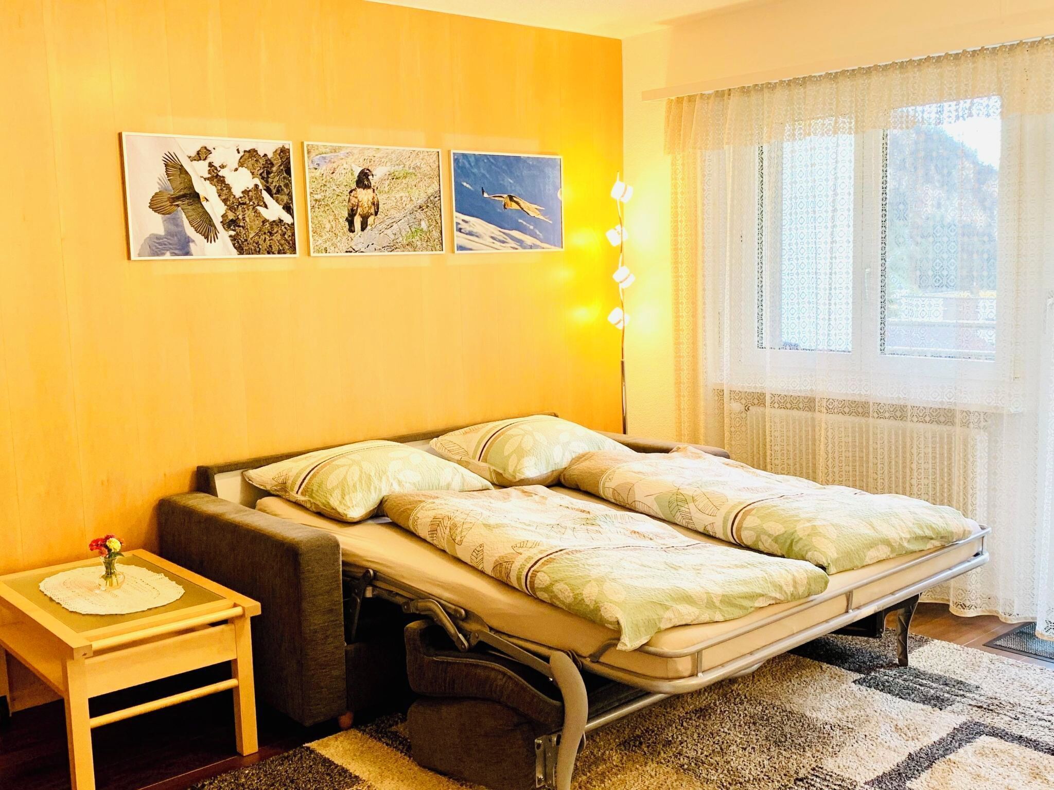 Una stanza con un letto, un comodino e una finestra con tende.