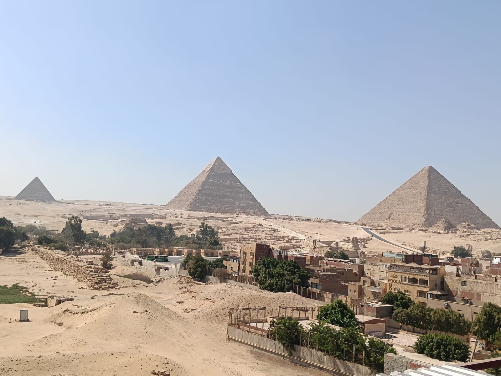 Vista de las pirámides de Giza, edificios circundantes y un cielo despejado.