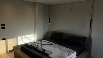 A modern bedroom with a bed, a bedside table, and a hanging light fixture.
