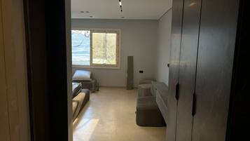 An interior space with a bed, a sofa, a cabinet, and a window with a view.