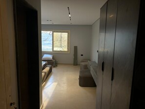 An interior space with a bed, a sofa, a cabinet, and a window with a view. - Royal Pyramids Land Hotel (Giza)