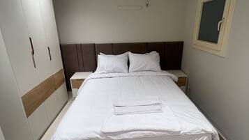 A hotel room with a bed, nightstands, a wardrobe, and a window.