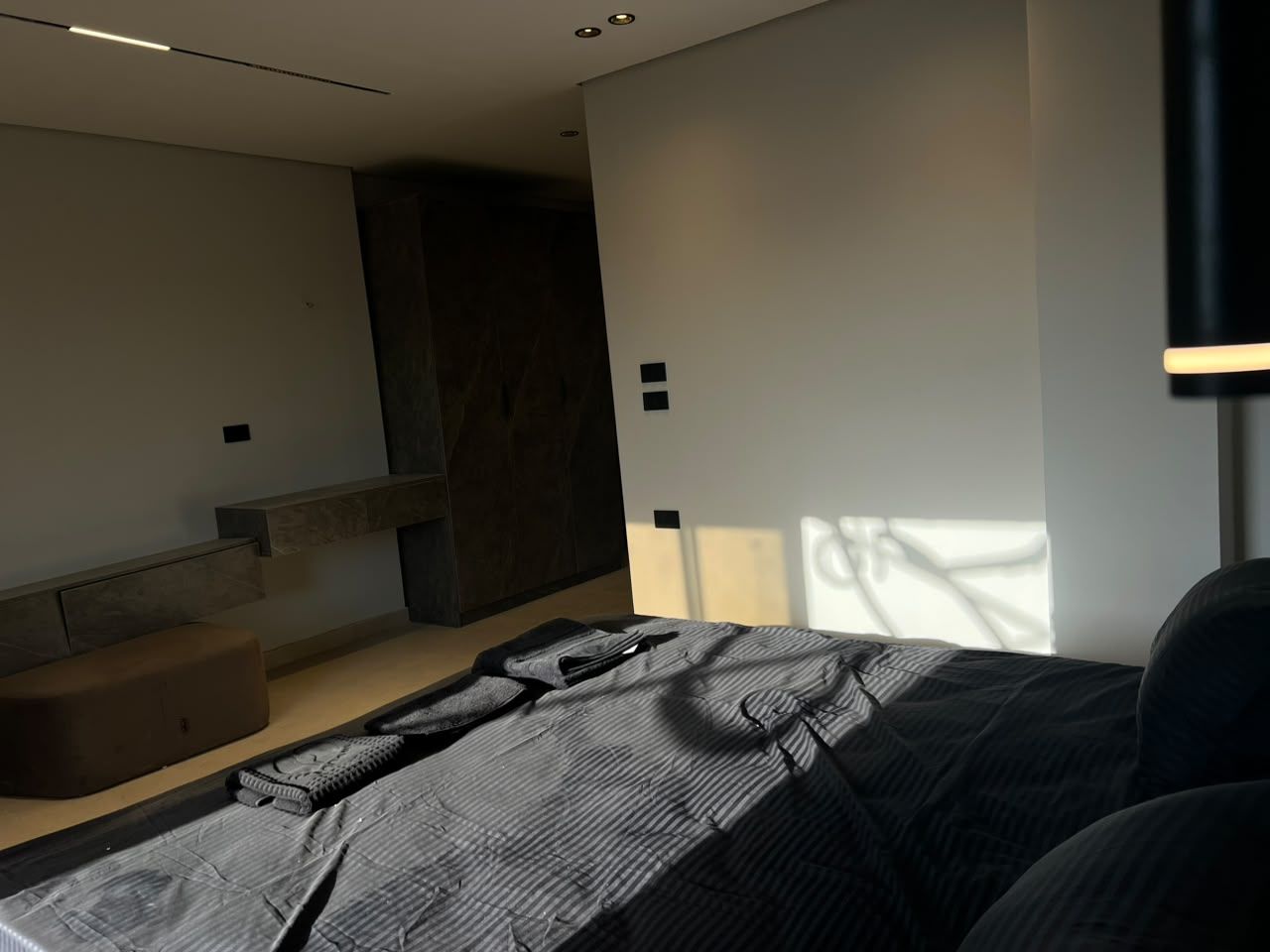 Un dormitorio moderno con una cama, un banco y una banqueta empotrada a lo largo de la pared.