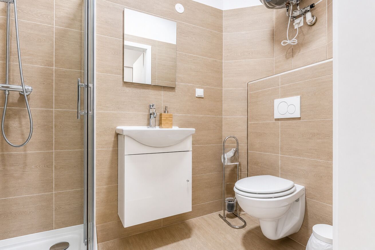 A modern bathroom with a shower, toilet, and sink.