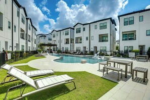 A modern apartment complex with a swimming pool, outdoor seating, and a well-maintained lawn. - Work + Unwind Poolside! Nurse-ready Houston Rental (Houston)