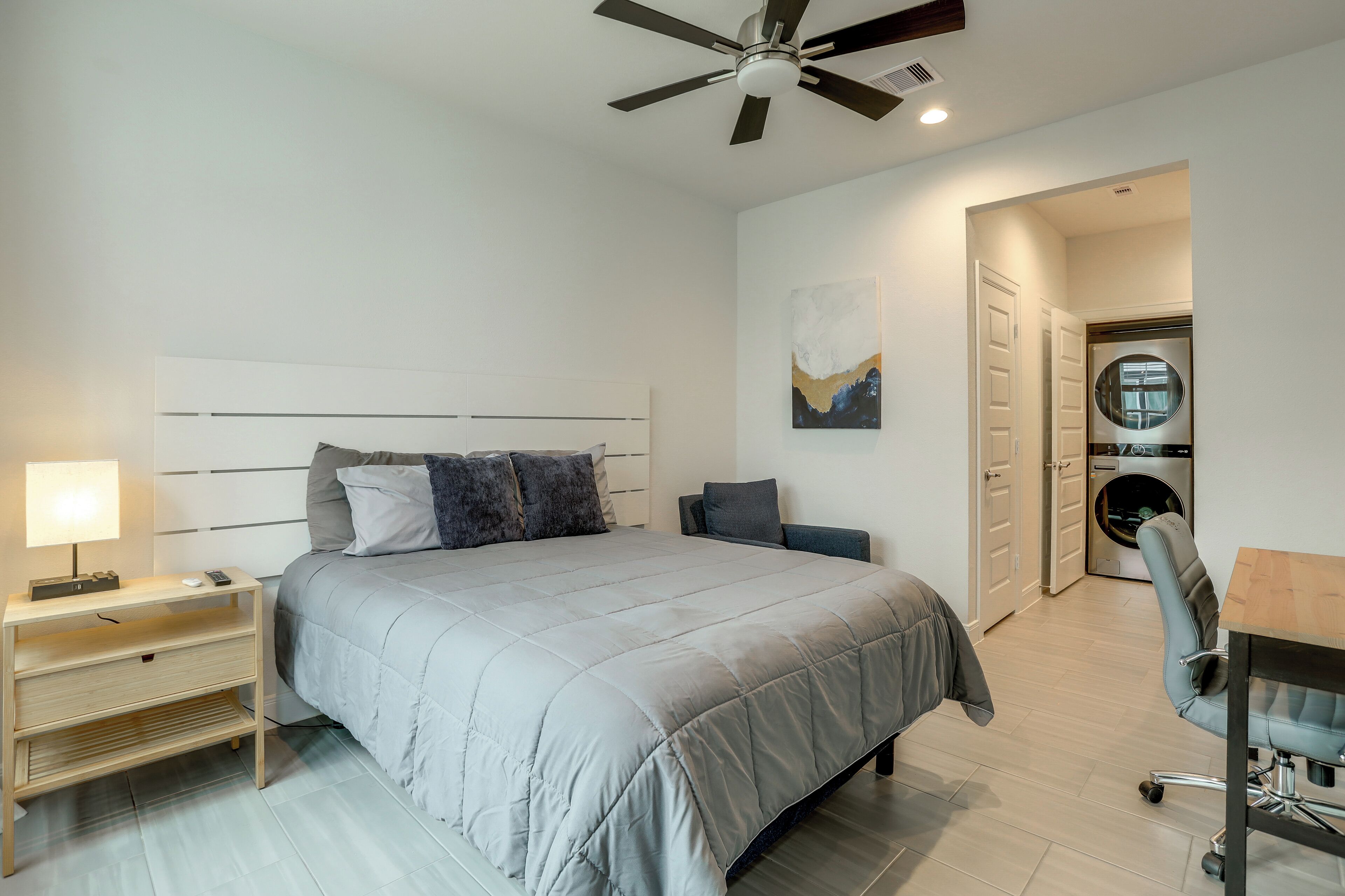 A bedroom with a bed, bedside table, lamp, and a ceiling fan.