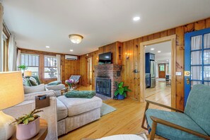 A cozy living room with a fireplace, wooden walls, and a television. - Sebago Lake Cottage Boat Mooring 2 Beaches (Windham)