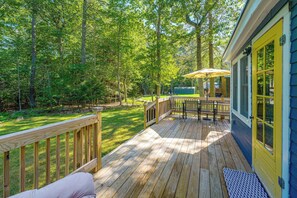 A wooden deck with outdoor furniture, a covered seating area, and a view of a forested area. - Sebago Lake Cottage Boat Mooring 2 Beaches (Windham)