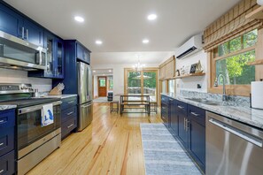 A modern kitchen with stainless steel appliances, wooden flooring, and a view of the outdoors. - Sebago Lake Cottage Boat Mooring 2 Beaches (Windham)