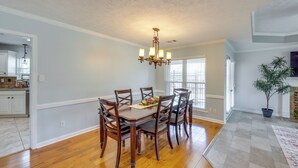 A dining area with a wooden table and chairs, a chandelier, and a potted plant. - Poolside Paradise w/ Game Room! Prattville Getaway (Prattville)