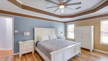 A bedroom with a bed, nightstands, a ceiling fan, a wardrobe, and a window with blinds.