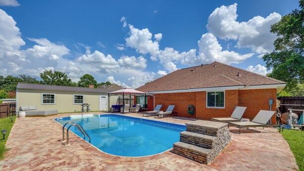 A backyard with a swimming pool, a covered patio area, and a brick house. - Poolside Paradise w/ Game Room! Prattville Getaway (Prattville)