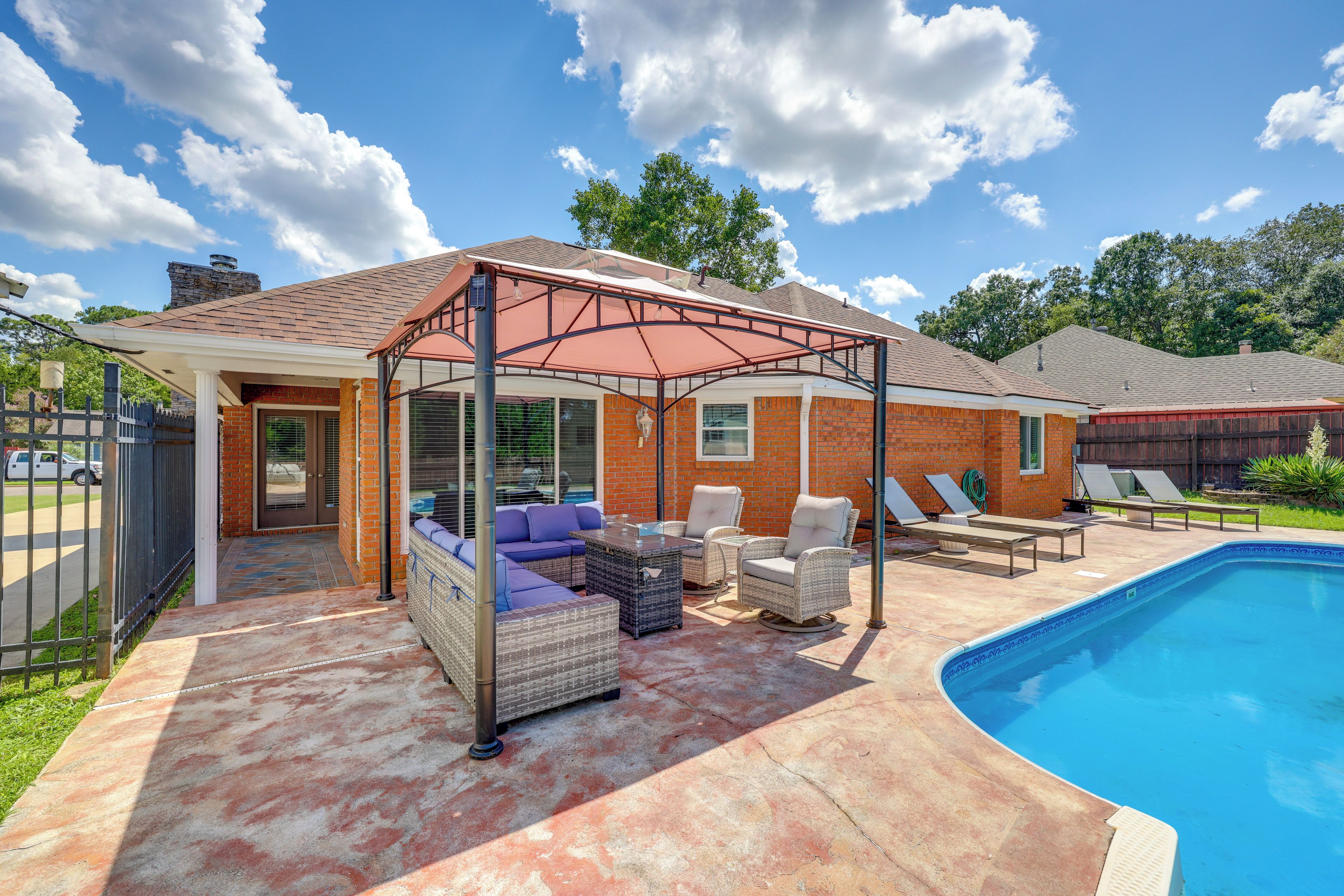 A backyard with a covered patio, outdoor seating, and a swimming pool.