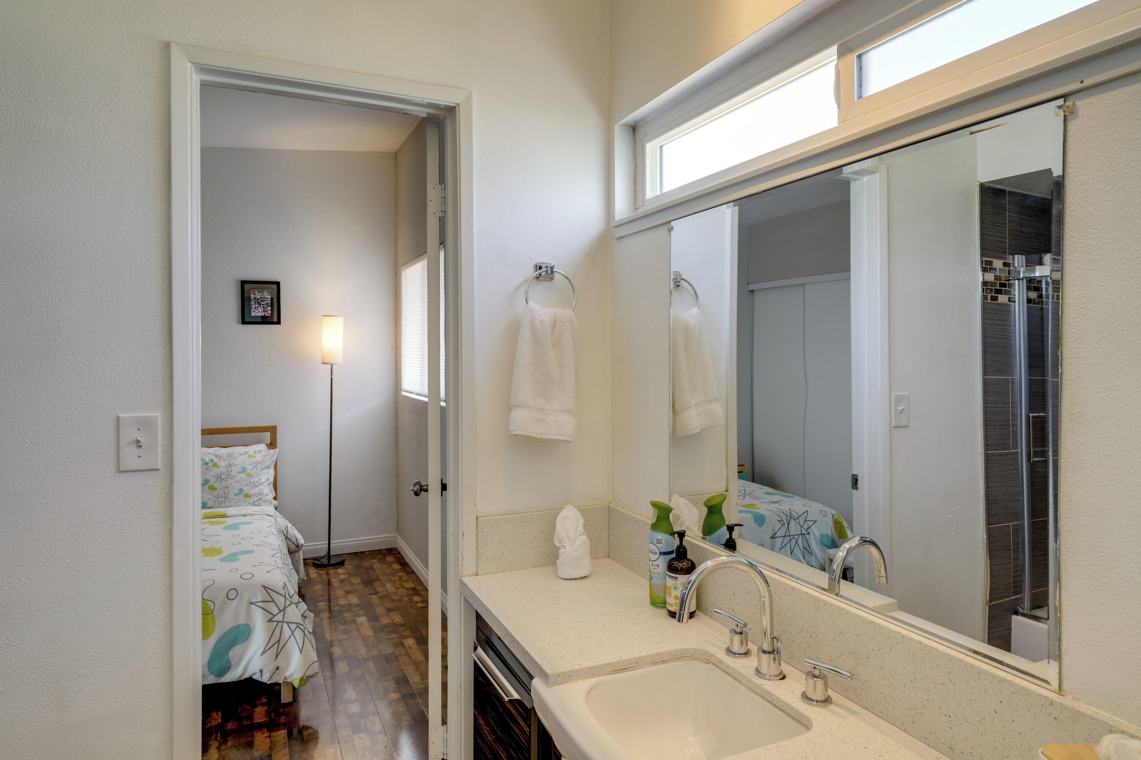 A bathroom with a large mirror, a sink, and a shower.
